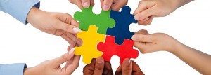 Image of hands holding multi coloured puzzle pieces together