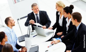 Image of business people sitting around a desk with papers and laptop on the table